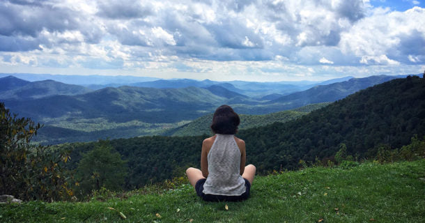 Woman sitting cross legged looking at mountain landscape