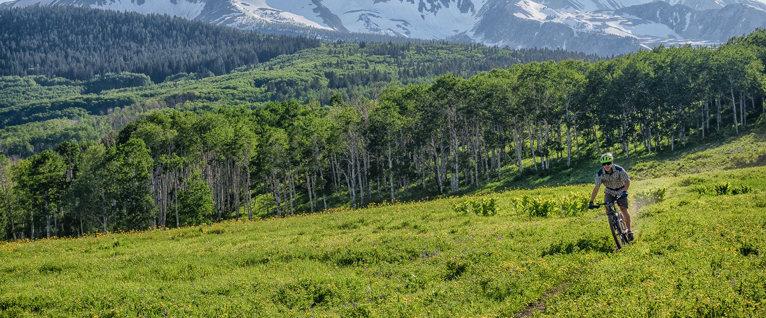 Man biking on trail with mountain backdrop