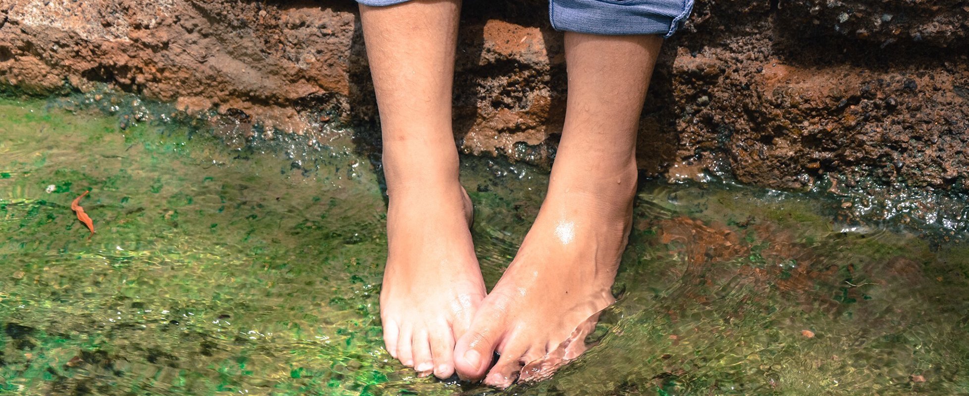 woman's feet in shallow creek