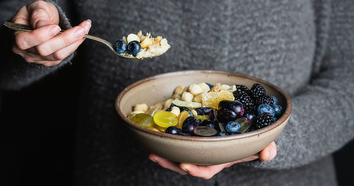 Woman eating bowl of oatmeal topped with fruit