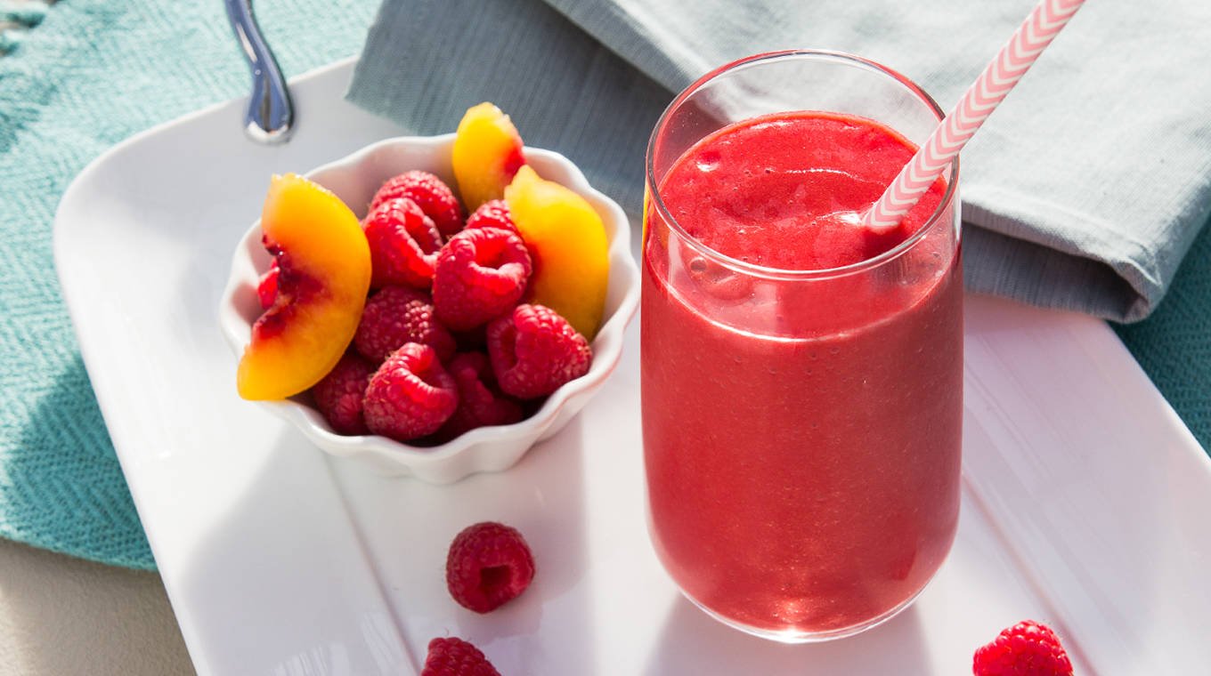 Sunset Raspberry Peach Smoothie with bowl of fruit on side