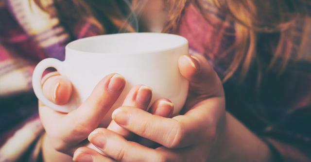Woman wearing plaid shirt holding cup of tea