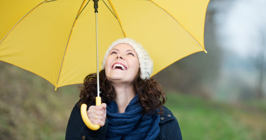 Happy woman looking up while holding an umbrella
