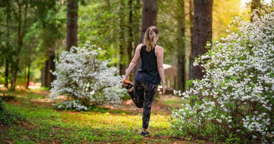 woman stretching for run near blooming bushes