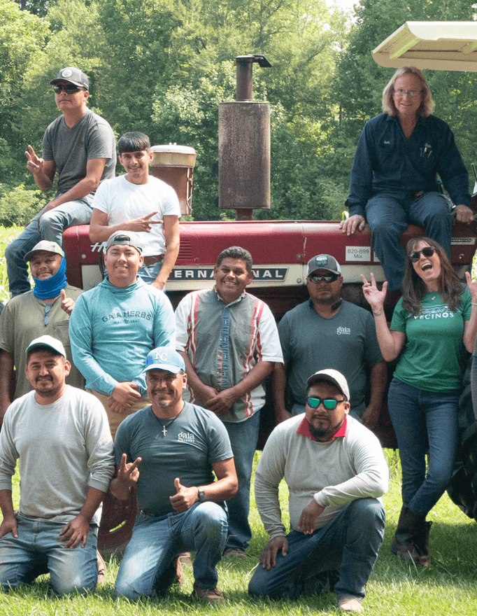 Group of people posing in front of a red tractor with trees in the background
