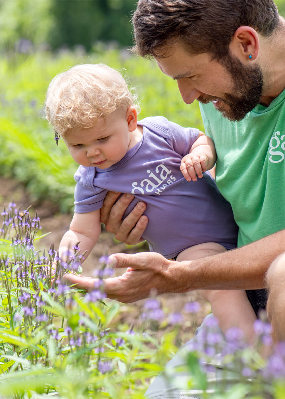 Man holding a baby in a field of flowers