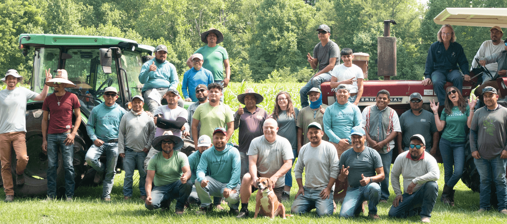 Group of people posing in front of farm equipment on a sunny day