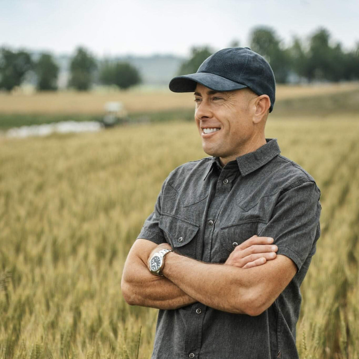 Jeff Tkach, CEO of Rodale Institute standing in a field with arms crossed, wearing a cap and gray shirt.