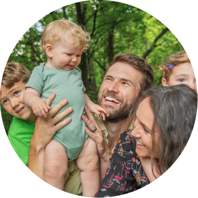 Family of four outdoors with a baby held by a man