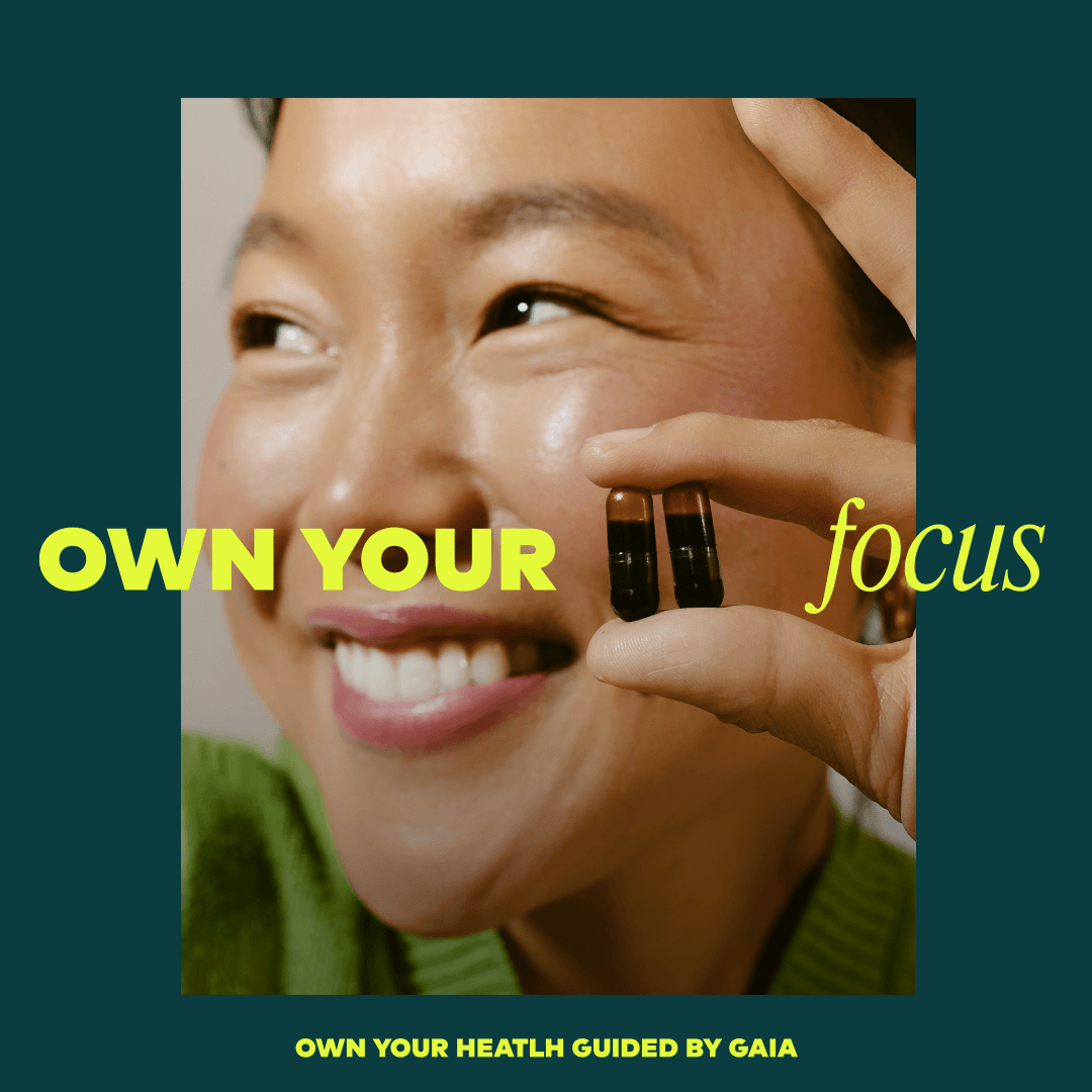 A promotional graphic with a close-up photo of a smiling woman holding two small dark capsules near her face. Large yellow text reads 'OWN YOUR focus' across the center, and smaller text at the bottom reads 'OWN YOUR HEALTH GUIDED BY GAIA'.