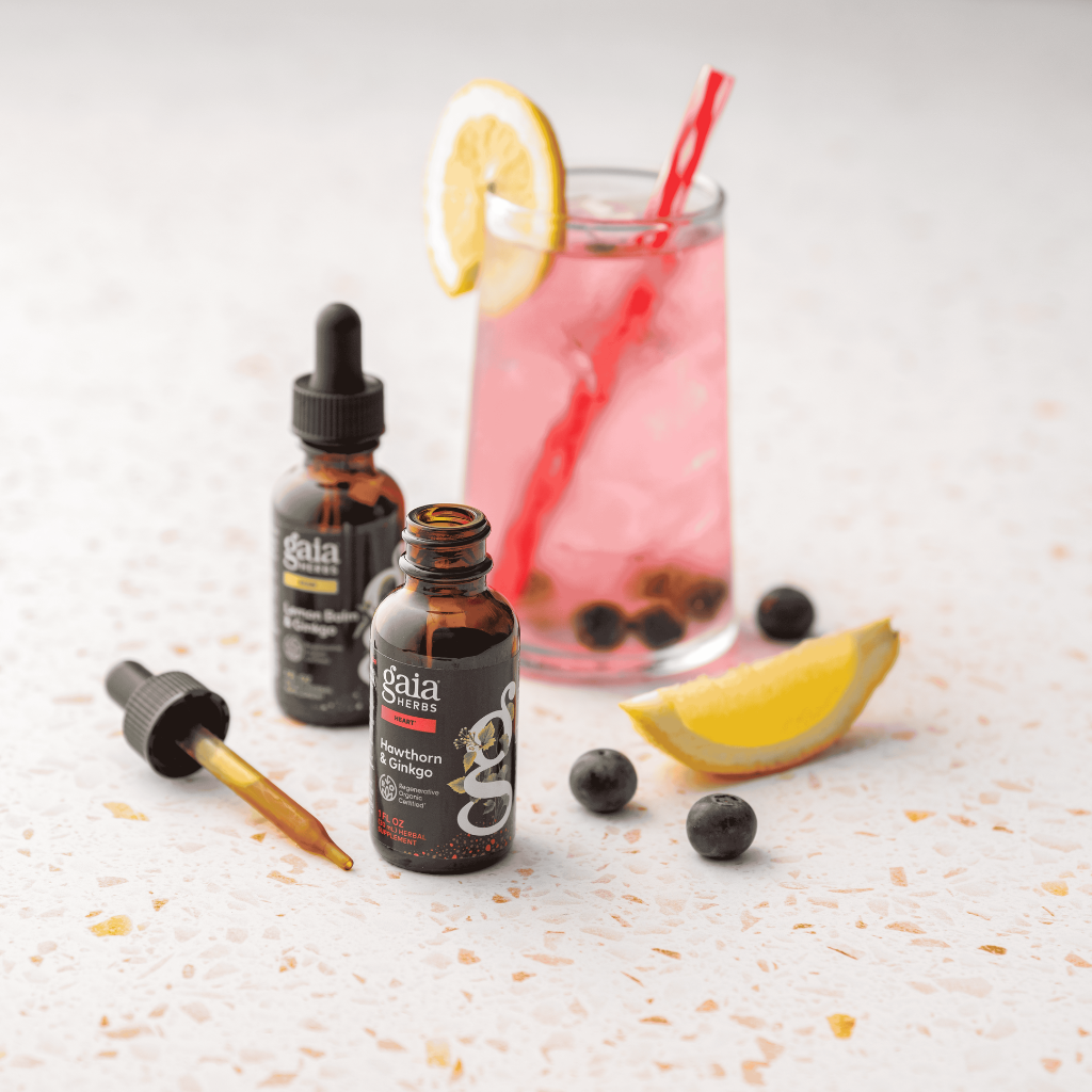 Gaia Herbs tinctures with a glass of lemonade on a textured surface