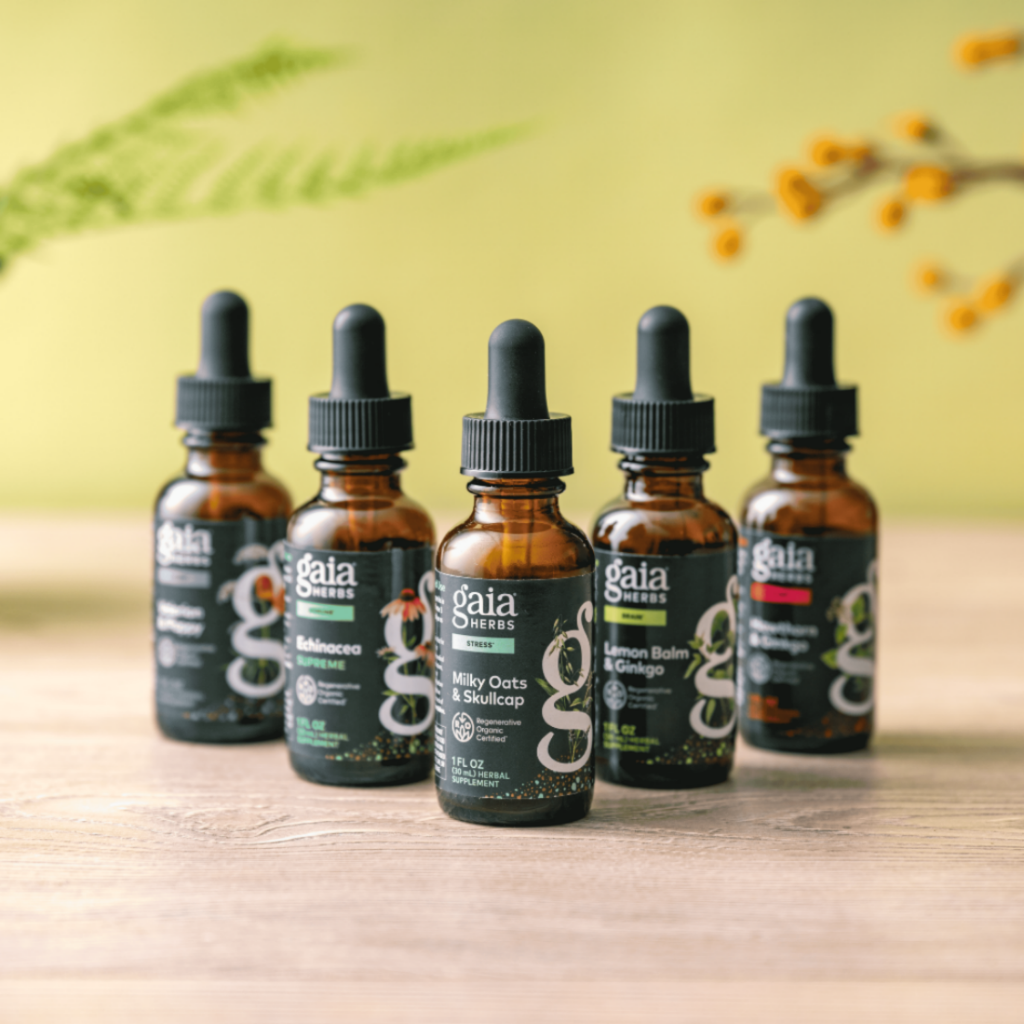 Five Gaia Herbs tincture bottles on a wooden surface with a blurred natural background